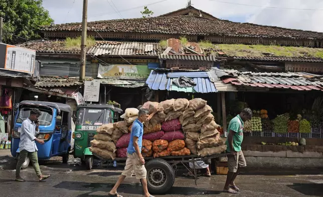 Workers pull a hand cart loaded with sacks of vegetables through a wholesale market in Colombo, Sri Lanka, Friday, Sept. 13, 2024. (AP Photo/Eranga Jayawardena)