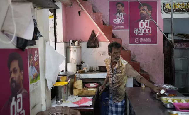 Election posters showing portraits of National People's Power's presidential candidate Anura Dissanayake, are pasted on the kitchen walls of an eatery where a cook prepares food for customers in Colombo, Sri Lanka, Monday, Sept. 16, 2024. (AP Photo/Eranga Jayawardena)