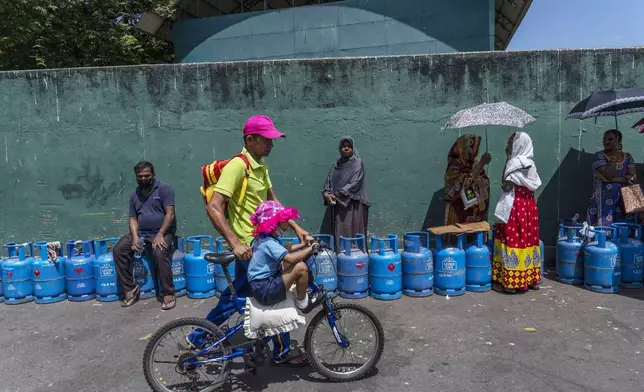 FILE - People wait in a queue with empty cylinders to buy domestic gas at a distribution center, in Colombo, Sri Lanka, on July 12, 2022. (AP Photo/Rafiq Maqbool, File)