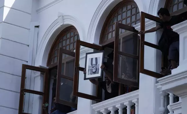 FILE - A protester holds a portrait of former Sri Lankan Prime Minister Mahinda Rajapaksa upside down after storming the Prime Minister Ranil Wickremesinghe's office demanding he resign after president Gotabaya Rajapaksa fled the country amid economic crisis, in Colombo, Sri Lanka, on July 13, 2022. (AP Photo/Eranga Jayawardena, File)