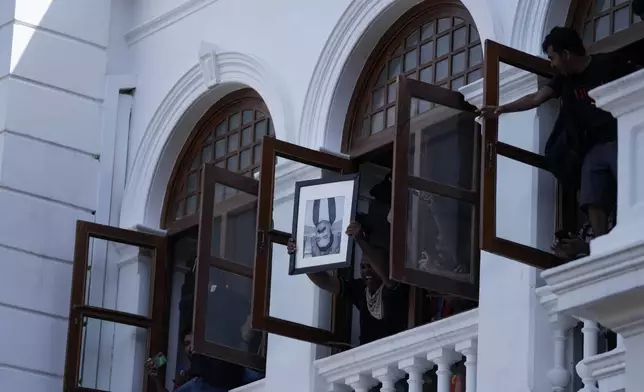 FILE - A protester holds a portrait of former Sri Lankan Prime Minister Mahinda Rajapaksa upside down after storming the Prime Minister Ranil Wickremesinghe's office demanding he resign after president Gotabaya Rajapaksa fled the country amid economic crisis, in Colombo, Sri Lanka, Wednesday, July 13, 2022. (AP Photo/Eranga Jayawardena, File)