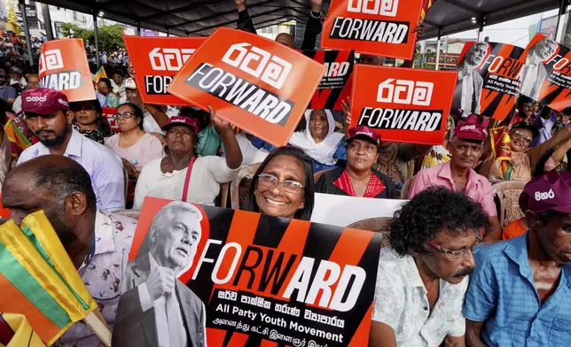 A woman supporter of Sri Lankan President and independent presidential candidate Ranil Wickremesinghe, holds a placard at an election rally in Minuwangoda, Sri Lanka, Tuesday, Sept. 17, 2024. (AP Photo/Rajesh Kumar Singh)