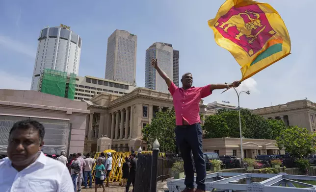 A supporter waves Sri Lankan flag as he waits for the swearing in ceremony of president elect Marxist lawmaker Anura Kumara Dissanayake out side president's office in Colombo, Sri Lanka, Monday, Sept. 23, 2024. (AP Photo/Eranga Jayawardena)