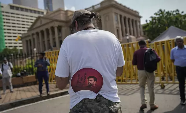 A supporter tucks a portrait of president elect Marxist lawmaker Anura Kumara Dissanayake on to his trousers as he waits for the swearing in ceremony outside president's office in Colombo, Sri Lanka, Monday, Sept. 23, 2024. (AP Photo/Eranga Jayawardena)