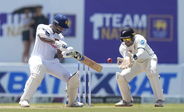 Sri Lanka's Dimuth Karunaratne plays a shot as New Zealand's Tom Blundell watches during the day one of the first test cricket match between Sri Lanka and New Zealand in Galle, Sri Lanka, Thursday, Sept. 26, 2024. (AP Photo/Eranga Jayawardena)