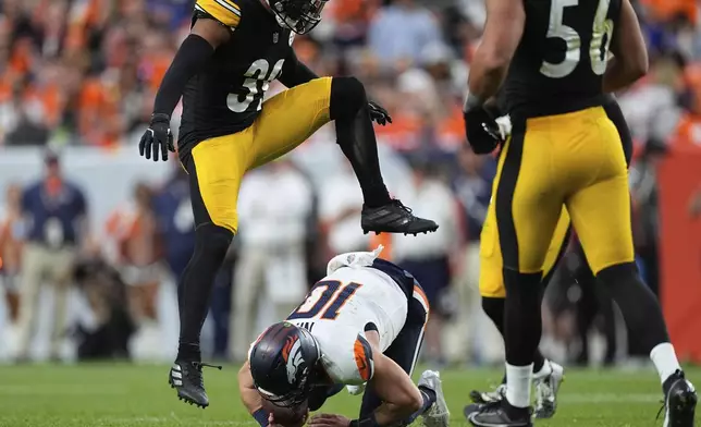 Denver Broncos quarterback Bo Nix (10) falls after a short gain as Pittsburgh Steelers safety Minkah Fitzpatrick (39) leaped over him during the second half of an NFL football game, Sunday, Sept. 15, 2024, in Denver. (AP Photo/David Zalubowski)