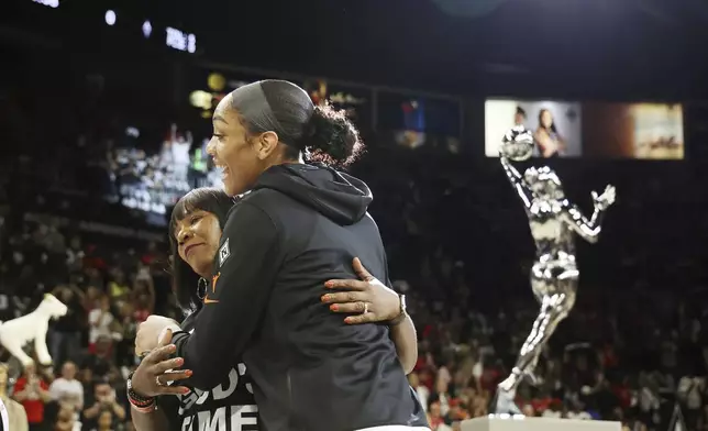 Las Vegas Aces center A'ja Wilson (22) embraces mother Eva Wilson and receives the 2024 WMBA MVP award prior to playing in a first-round WNBA basketball playoff game against the Seattle Storm Sunday, Sept. 22, 2024, in Las Vegas. (AP Photo/Ronda Churchill)