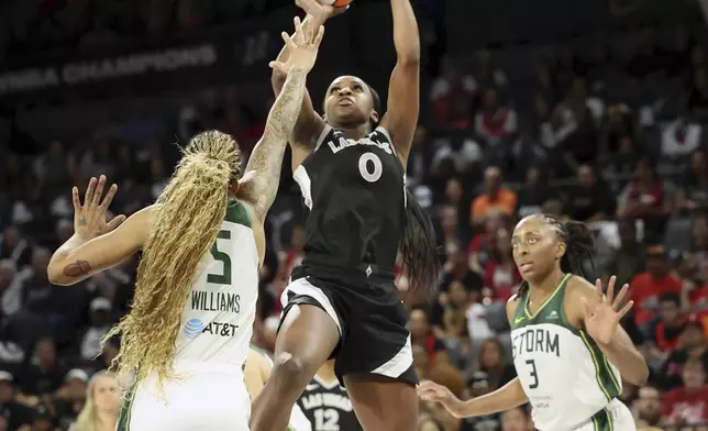 Las Vegas Aces guard Jackie Young (0) shoots the ball near Seattle Storm forwards Gabby Williams (5) and Nneka Ogwumike (3) during a first-round WNBA basketball playoff game Sunday, Sept. 22, 2024, in Las Vegas. (AP Photo/Ronda Churchill)