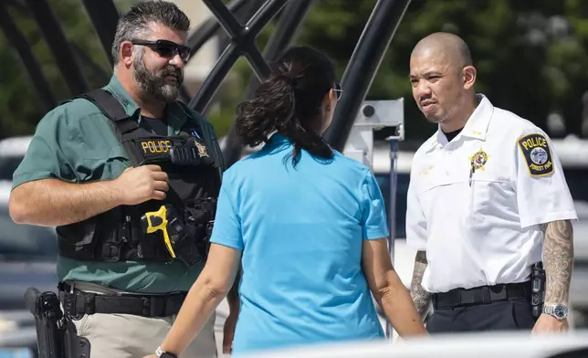 Forest Park Deputy Chief Christopher Chin, right, stands outside the Forest Park Blue Line train station in Forest Park, Ill., after giving a news conference about four people who were fatally shot on the train early Monday, Sept. 2, 2024. (Pat Nabong/Chicago Sun-Times via AP)