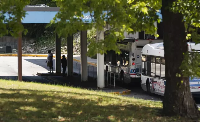 Commuters wait for a bus outside the Forest Park Blue Line train station in Forest Park, Ill., which remains closed, after four people were fatally shot on the train early Monday, Sept. 2, 2024. (Pat Nabong/Chicago Sun-Times via AP)