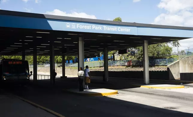 Commuters wait for a bus outside the Forest Park Blue Line train station in Forest Park, Ill., which remains closed, after four people were fatally shot on the train early Monday, Sept. 2, 2024. (Pat Nabong/Chicago Sun-Times via AP)