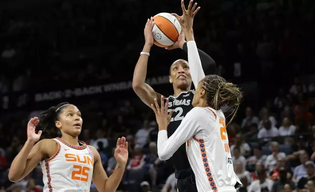 Las Vegas Aces center A'ja Wilson (22) shoots between Connecticut Sun forwards Alyssa Thomas (25) and DeWanna Bonner (24) during the first half of a WNBA basketball game Sunday, Sept. 15, 2024, in Las Vegas. (Steve Marcus/Las Vegas Sun via AP)