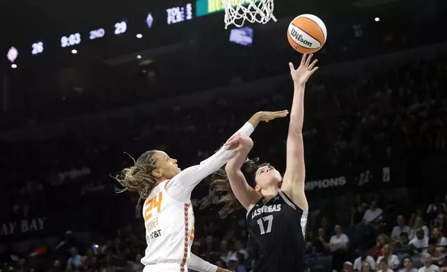 Las Vegas Aces center Megan Gustafson (17) shoots a layup against Connecticut Sun forward DeWanna Bonner (24) during the first half of a WNBA basketball game Sunday, Sept. 15, 2024, in Las Vegas. (Steve Marcus/Las Vegas Sun via AP)