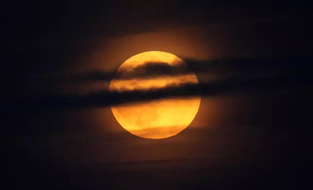 The moon rises through clouds over the Atlantic Ocean off the coast of Camden, Maine, Tuesday, Sept. 17, 2024. (AP Photo/Robert F. Bukaty)