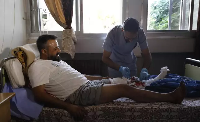 A Syrian nurse treats an man who was injured in the town of Masyaf, Syria, Monday, Sept. 9, 2024. Syrian state news agency SANA says that Israeli strikes hit several areas in central Syria Sunday night, damaging a highway in Hama province and sparking fires. (AP Photo/Omar Sanadiki)