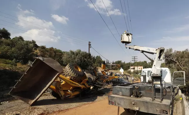 Syrian workers stand on a crane next of a flipped bulldozer in the town of Masyaf, Syria, Monday, Sept. 9, 2024. Syrian state news agency SANA says that Israeli strikes hit several areas in central Syria Sunday night, damaging a highway in Hama province and sparking fires. (AP Photo/Omar Sanadiki)