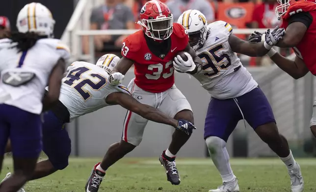 Georgia running back Chauncey Bowers (33) runs between Tennessee Tech linebacker Kalvyn Crummie (42) and defensive lineman Jeremiah Sandiford (95) during the second half of an NCAA college football game Saturday, Sept. 7, 2024, in Athens, Ga. (AP Photo/John Bazemore)