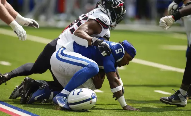 Indianapolis Colts quarterback Anthony Richardson (5) loses his helmet as he is sacked by Houston Texans defensive end Mario Edwards Jr. (97) during the first half of an NFL football game, Sunday, Sept. 8, 2024, in Indianapolis. (AP Photo/Darron Cummings)