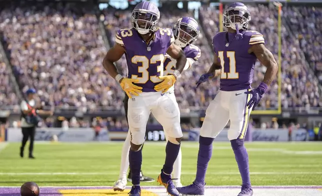 Minnesota Vikings running back Aaron Jones (33) celebrates with teammate wide receivers Justin Jefferson (18), center, and Trent Sherfield Sr. (11) after a 39-yard run during the second half of an NFL football game against the Houston Texans, Sunday, Sept. 22, 2024, in Minneapolis. (AP Photo/Abbie Parr)