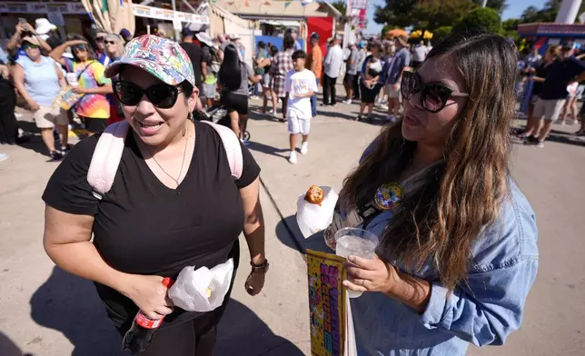 Jamie Rojas, left, and Elvira Torres, right, both of Dallas, respond to a reporter's questions regarding the ban on guns at the State Fair of Texas in Dallas, on Friday, Sept. 27, 2024. (AP Photo/Tony Gutierrez)