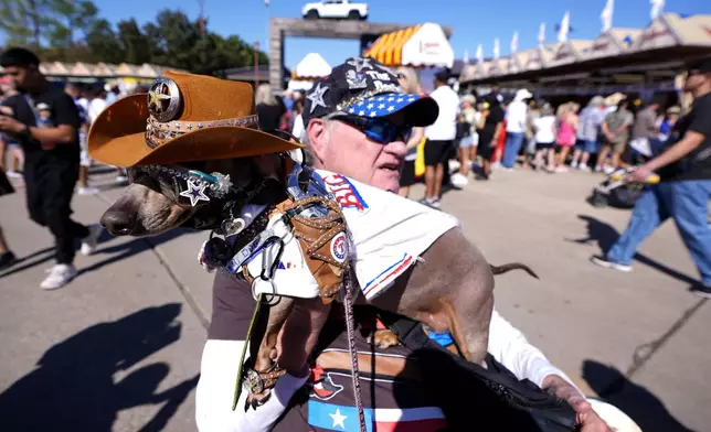 Bob Ankrum holds his service dog, Buttercup, who has a toy pistol fastened on to her shoulder, as they attend the State Fair of Texas in Dallas, on Friday, Sept. 27, 2024. (AP Photo/Tony Gutierrez)