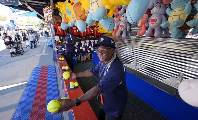 Artis Frank calls out to guests as they walk past a game attraction on the Super Midway at the State Fair of Texas in Dallas, Friday, Sept. 27, 2024. (AP Photo/Tony Gutierrez)