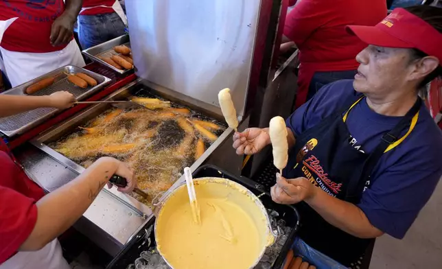 Luisa Lopez, right, helps prepare dozens of Fletchers corny dogs at their food booth at the State Fair of Texas in Dallas, Friday, Sept. 27, 2024. (AP Photo/Tony Gutierrez)