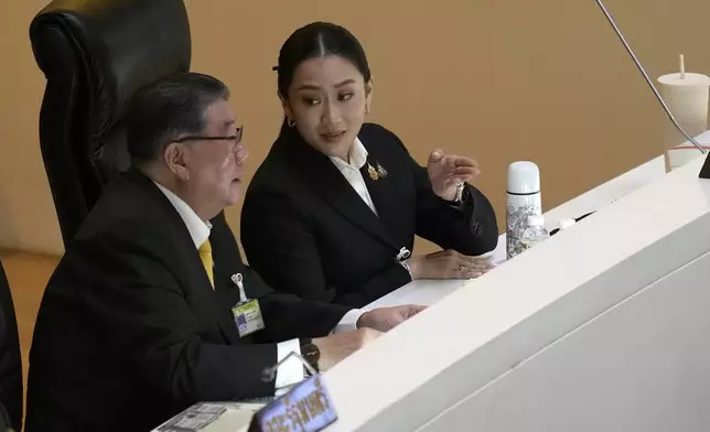 Thailand’s Deputy Prime Minister Phumtham Wechayachai, left, talks to Thailand's Prime Minister Paetongtarn Shinawatra before making the policy statement at parliament in Bangkok, Thailand, Thursday, Sept. 12, 2024. Paetongtarn appeared Parliament for the first time to lay out how her government envisions to improve the country. (AP Photo/Sakchai Lalit)