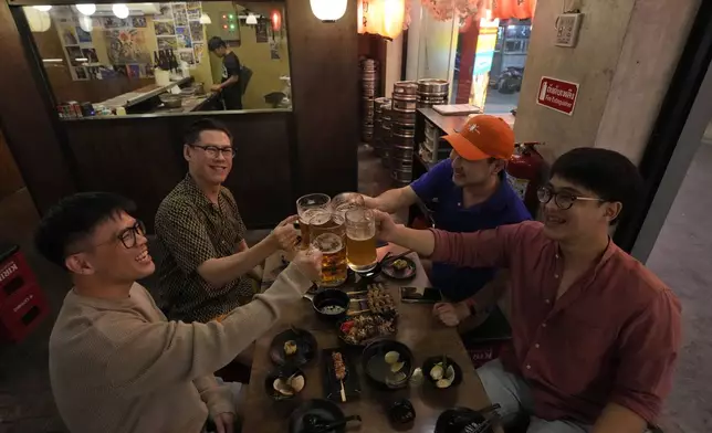 Edward Jonathan Caiga, 42, front left, and Kunchanok Khantiphong, 27, front right, raise a toast with their friends at the Banpuku Yokocho restaurant, where they had their first date, in Bangkok, Thailand, Saturday, July 6, 2024. (AP Photo/Sakchai Lalit)