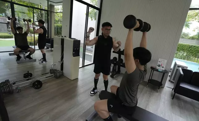 Kunchanok khantiphong, 27, lifts dumbbells watched by his Filipino partner Edward Jonathan Caiga, 42, in Bangkok, Thailand, Saturday, July 6, 2024. (AP Photo/Sakchai Lalit)