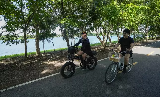 Edward Jonathan Caiga, 42, left, and his partner Kunchanok Khantiphong, 27, ride a bicycle at Nong Bon Lake Park in Bangkok, Thailand, Saturday, July 6, 2024. (AP Photo/Sakchai Lalit)