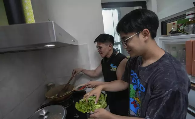 Kunchanok khantiphong, 27, right, and his Filipino partner Edward Jonathan Caiga ,42, cook a meal at home in Bangkok, Thailand, Saturday, July 6, 2024. (AP Photo/Sakchai Lalit)