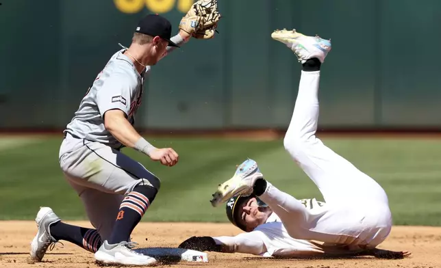 Oakland Athletics' Zack Gelof, right, slides into second base on a stolen base as Detroit Tigers shortstop Trey Sweeney, left, applies the tag during the fourth inning of a baseball game in Oakland, Calif., Sunday, Sept. 8, 2024. (AP Photo/Jed Jacobsohn)