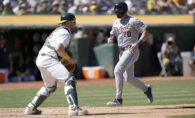 Detroit Tigers' Spencer Torkelson (20) scores a run past Oakland Athletics catcher Kyle McCann, left, on a sacrifice fly by Parker Meadows during the seventh inning of a baseball game Saturday, Sept. 7, 2024, in Oakland, Calif. (AP Photo/Tony Avelar)