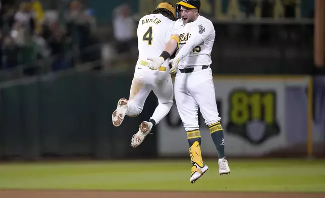 Oakland Athletics' Seth Brown (15) celebrates his game-winning single with Lawrence Butler (4) during the 13th inning against the Detroit Tigers in a baseball game Friday, Sept. 6, 2024, in Oakland, Calif. Oakland won 7-6. (AP Photo/Tony Avelar)