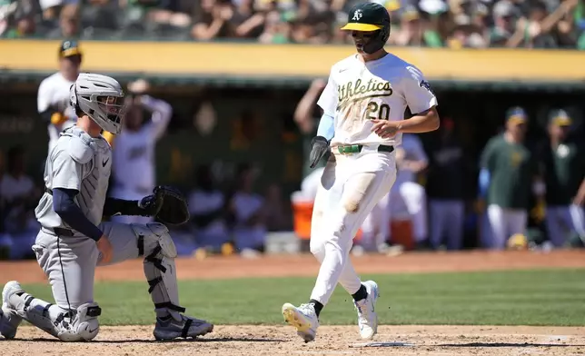 Oakland Athletics' Zack Gelof (20) scores a run past Detroit Tigers catcher Dillon Dingler, left, on a single by Kyle McCann during the fifth inning of a baseball game Saturday, Sept. 7, 2024, in Oakland, Calif. (AP Photo/Tony Avelar)