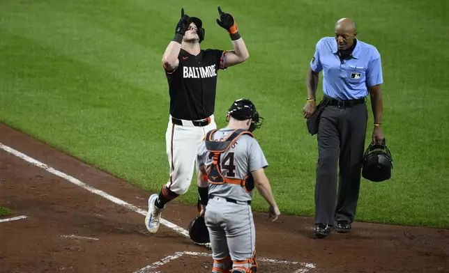 Baltimore Orioles' James McCann gestures as he celebrates his home run in front of Detroit Tigers catcher Jake Rogers (34) and home plate umpire CB Bucknor, right, during the sixth inning of a baseball game, Friday, Sept. 20, 2024, in Baltimore. (AP Photo/Nick Wass)