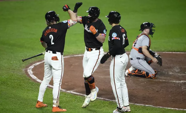 Baltimore Orioles' James McCann, second from left, celebrates after his two-run home run with Gunnar Henderson (2) and Coby Mayo (16) as Detroit Tigers catcher Jake Rogers., right, looks on during the fourth inning of a baseball game Friday, Sept. 20, 2024, in Baltimore. (AP Photo/Nick Wass)