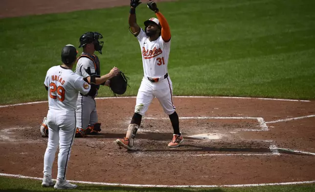 Baltimore Orioles' Cedric Mullins (31) celebrates after his two-run home run with Ramon Urias (29) during the fifth inning of a baseball game as Detroit Tigers catcher Jake Rogers, center, looks on Sunday, Sept. 22, 2024, in Baltimore. (AP Photo/Nick Wass)