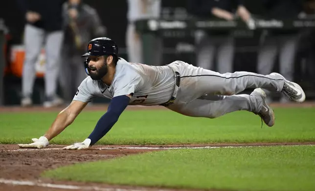 Detroit Tigers' Riley Greene dives towards home to score on a sacrifice fly by Zach McKinstry during the tenth inning of a baseball game against the Baltimore Orioles, Saturday, Sept. 21, 2024, in Baltimore. (AP Photo/Nick Wass)