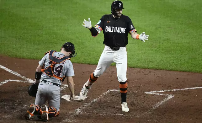 Baltimore Orioles' Colton Cowser, top, celebrates his home run during the sixth inning of a baseball game as Detroit Tigers catcher Jake Rogers looks on, at bottom, Friday, Sept. 20, 2024, in Baltimore. (AP Photo/Nick Wass)