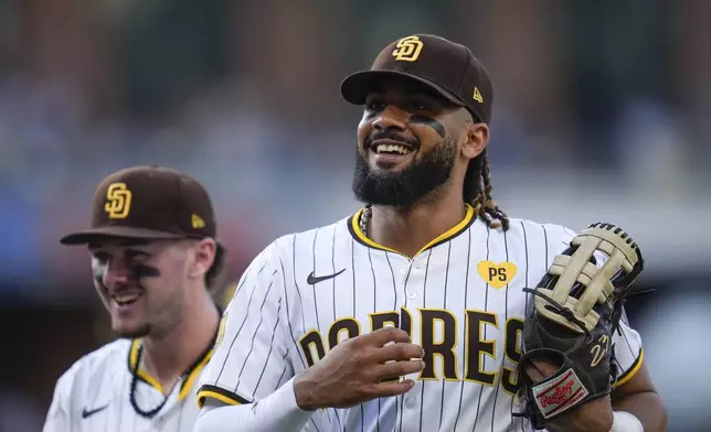 San Diego Padres right fielder Fernando Tatis Jr., right, jokes with teammate centerfielder Jackson Merrill during the seventh inning of a baseball game Monday, Sept. 2, 2024, in San Diego. (AP Photo/Gregory Bull)