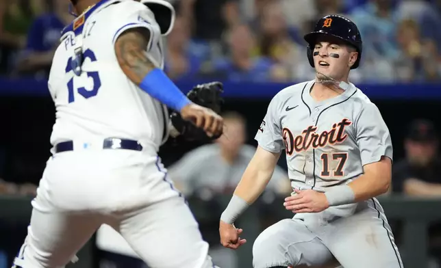 Detroit Tigers' Jace Jung (17) beats the tag by Kansas City Royals catcher Salvador Perez to score on a double by Trey Sweeney during the third inning of a baseball game Wednesday, Sept. 18, 2024, in Kansas City, Mo. (AP Photo/Charlie Riedel)