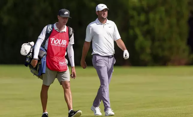 Scottie Scheffler, right, and his caddie walk to his drive on the fairway of the seventh hole during the third round of the Tour Championship golf tournament, Saturday, Aug. 31, 2024, in Atlanta. (AP Photo/Jason Allen)