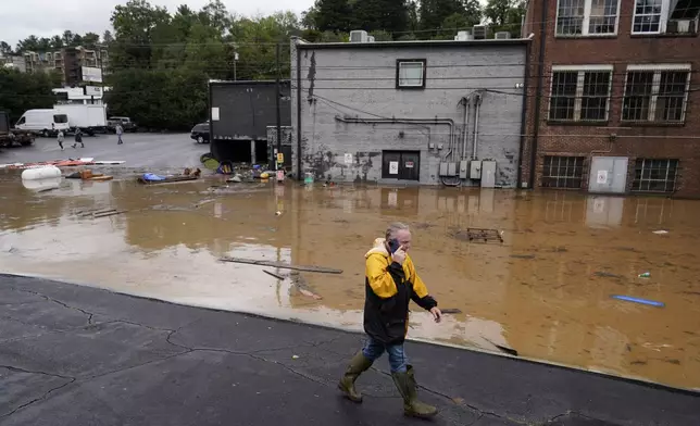 A man walks near a flooded area near the Swannanoa river, effects from Hurricane Helene , Friday, Sept. 27, 2024, in Asheville, N.C. (AP Photo/Erik Verduzco)