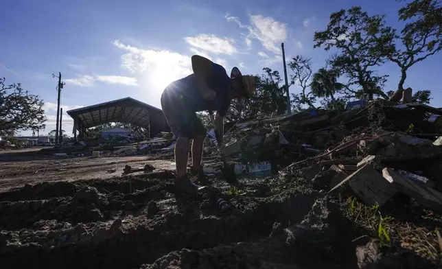 Chris Jordan, maintenance manager for Horseshoe Beach, tries to find a water shutoff valve amid the rubble of the destroyed city hall in the aftermath of Hurricane Helene, in Horseshoe Beach, Fla., Sunday, Sept. 29, 2024. (AP Photo/Gerald Herbert)