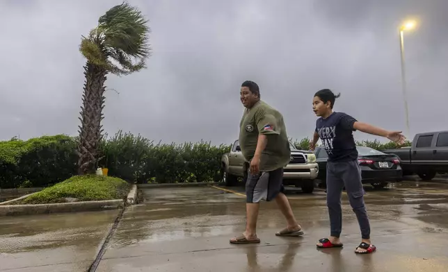 Lazaro Cardoso, 11, leans far into the powerful winds coming from the eye wall of Hurricane Francine as he and his dad, Hugo Gonzales, stay at a hotel in Houma, Louisiana that was being powered by a generator on Wednesday, Sept. 11, 2024, in Houma, La. The family lives not far from the hotel but they decided to stay at it since they said they always lose power during powerful storms. (Chris Granger/The Times-Picayune/The New Orleans Advocate via AP)