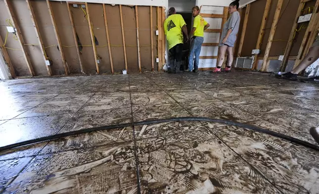 Workers clean and gut a property that was flooded from the storm surge, in the aftermath of Hurricane Helene, in Steinhatchee, Fla., Sunday, Sept. 29, 2024. (AP Photo/Gerald Herbert)