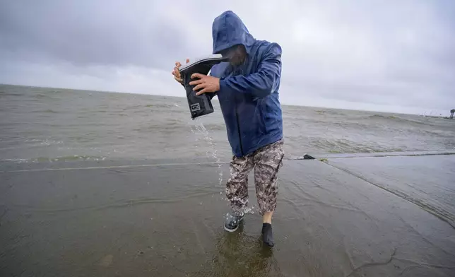 Conrad Bach drains water from his boot after getting doused while looking at waves from the wind from Hurricane Francine along Lakeshore Drive and Lake Ponchartrain in New Orleans, Wednesday, Sept. 11, 2024. (AP Photo/Matthew Hinton)