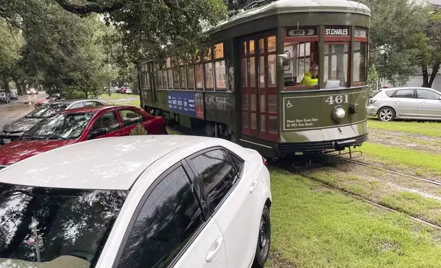 A streetcar eases past cars parked on the median in anticipation of street flooding from Tropical Storm Francine on South Carrollton Avenue in New Orleans, Wednesday, Sept. 11, 2024. (AP Photo/Kevin McGill)